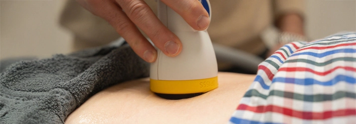 A softwave therapy device against a patient's back
